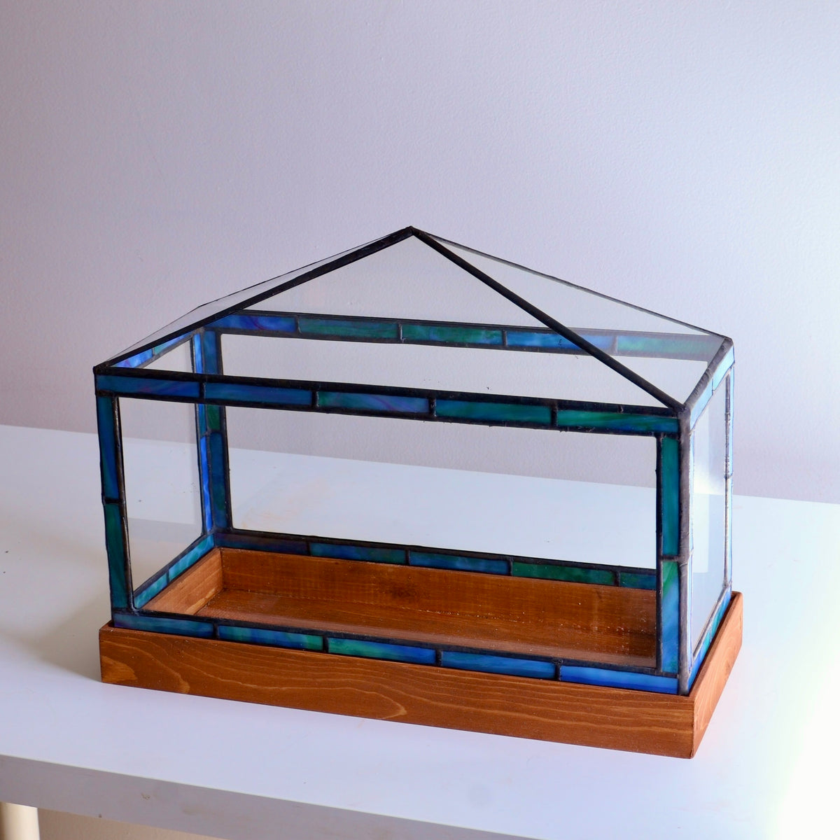 Stained-glass display case with blue and green glass on a white surface