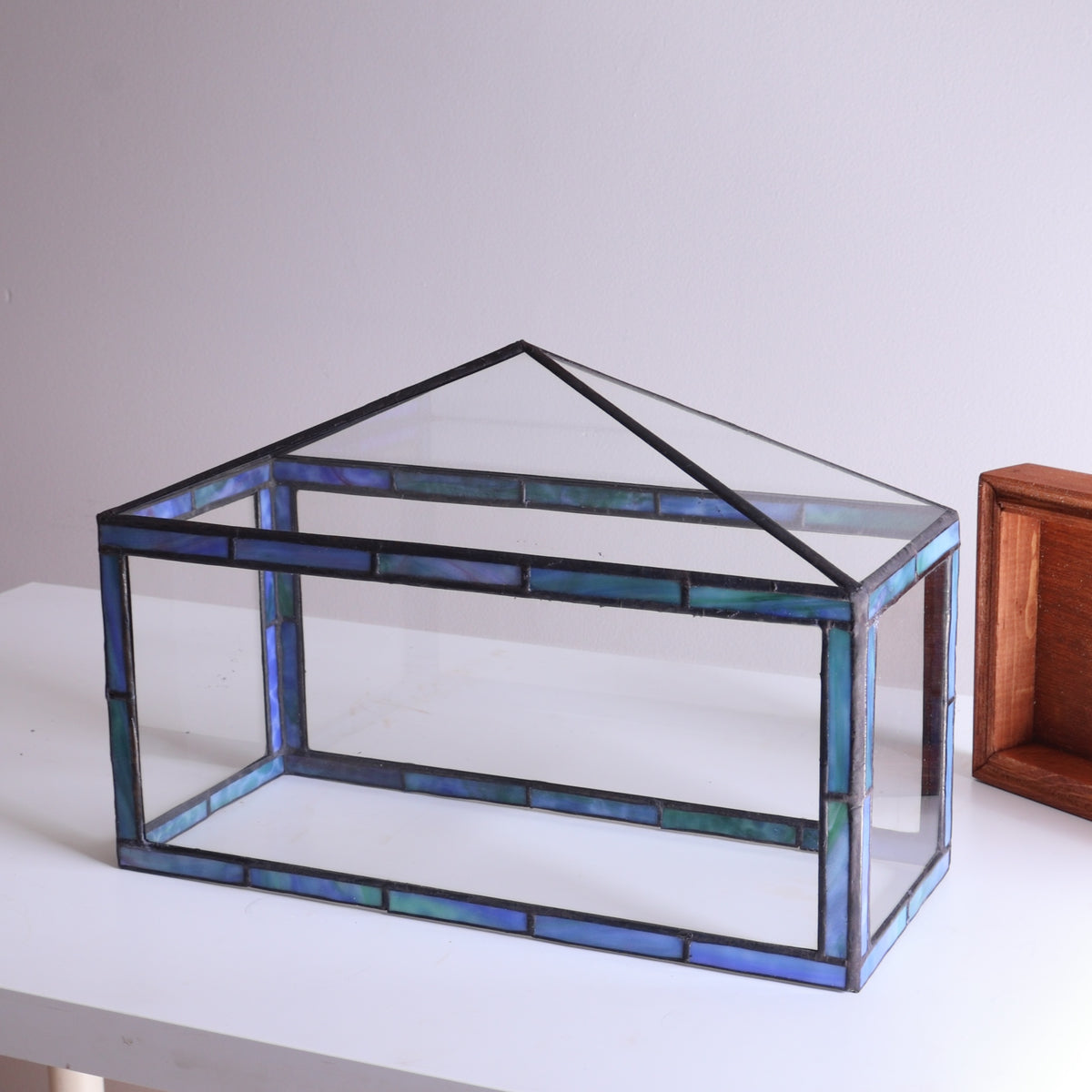 Glass terrarium with stained glass design on a white surface