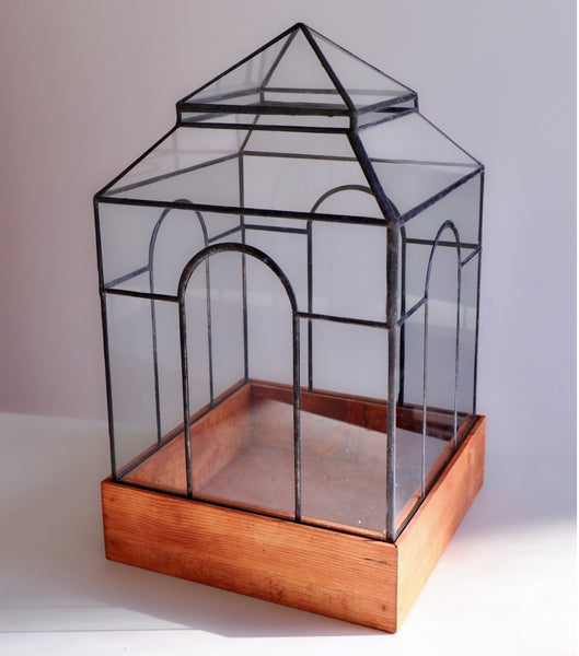 A large midcentury glass terrarium with four arches.