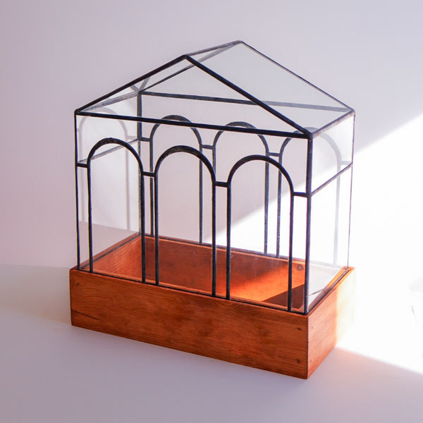 A glass terrarium with intricate stained glass design