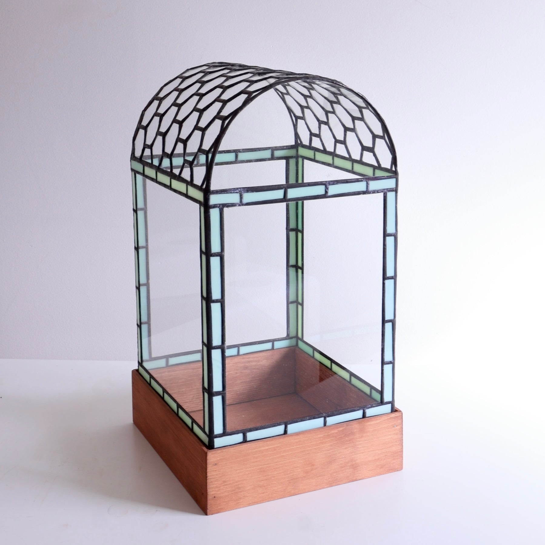 Stained glass display case with honeycomb curved top on wooden base on a white background