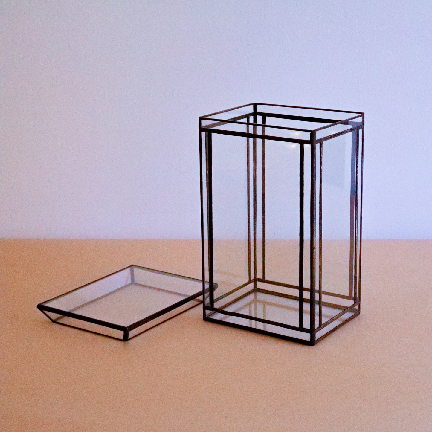 A terrarium made of stained glass with the top off. 