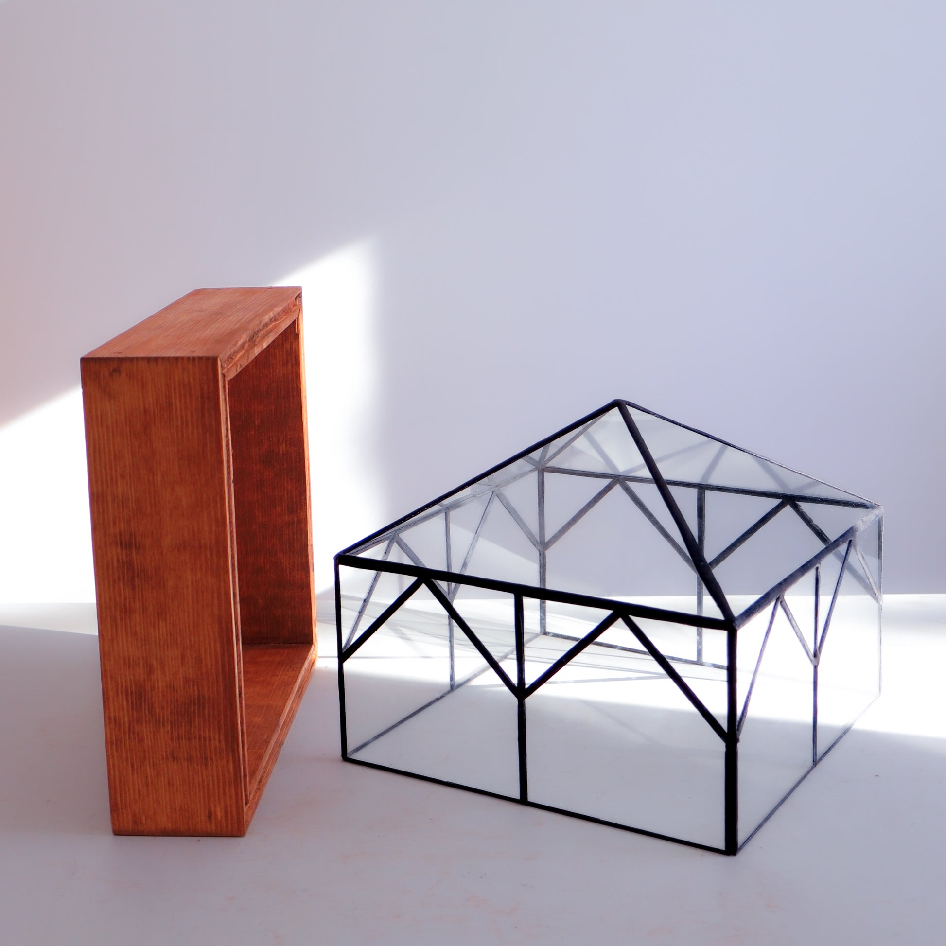 A stained glass terrarium next to its wood base. 