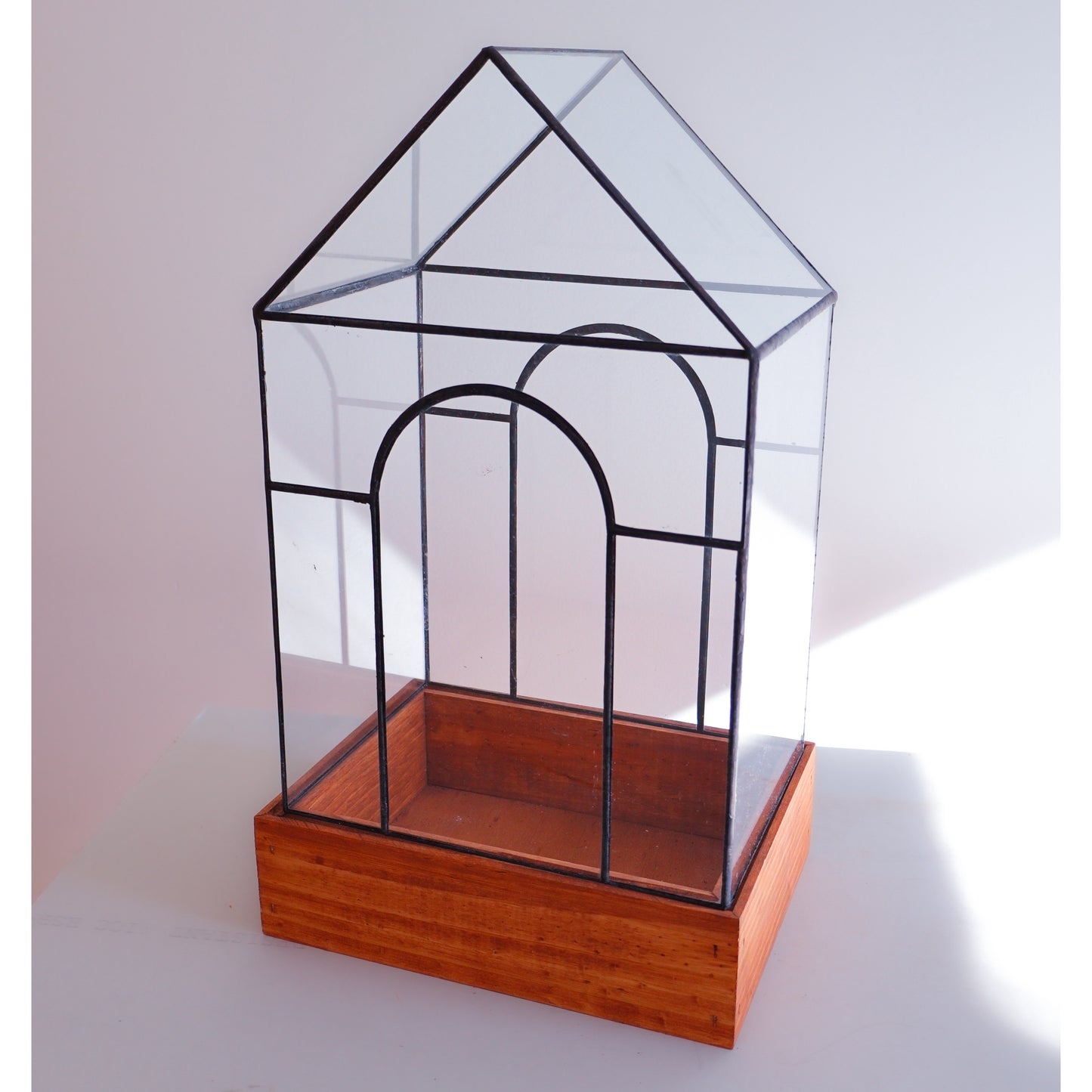 A terrarium for plants with two arches and a tall glass top. 