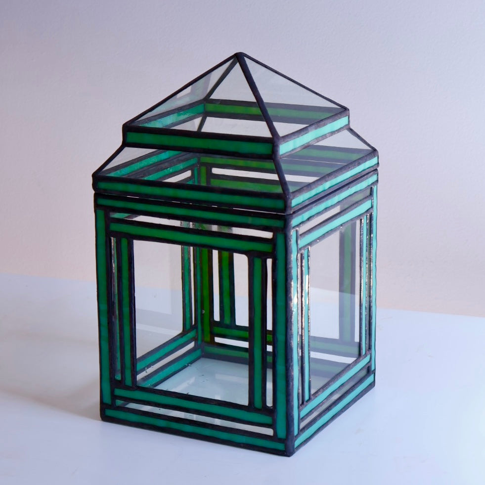 Green glass terrarium on a white surface with a light gray background