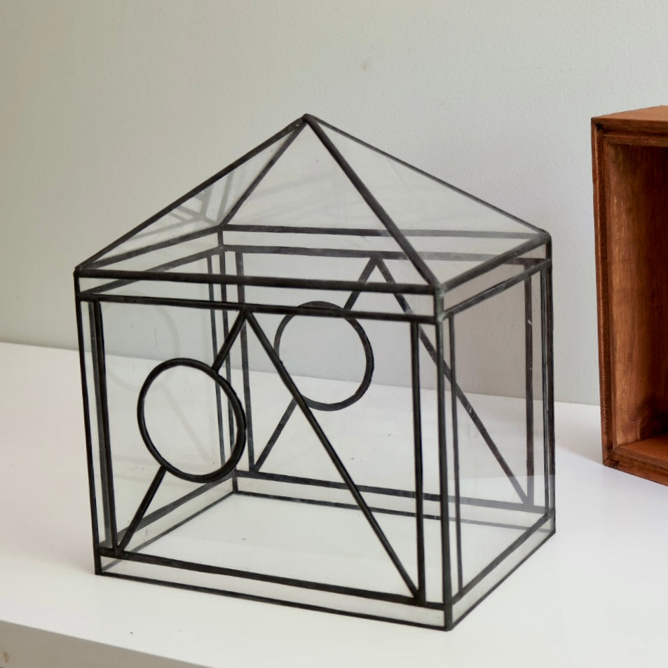 Geometric glass terrarium on a white surface with a neutral background
