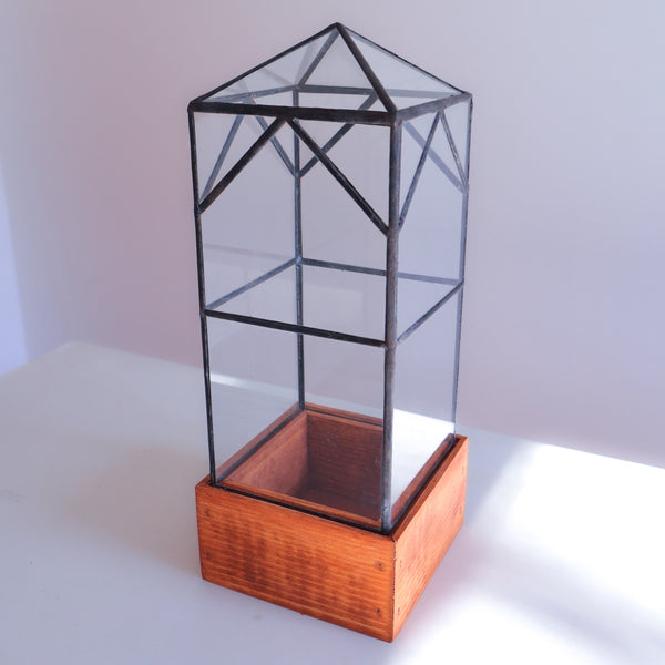 A stained glass terrarium handcrafted with a wood base. 
